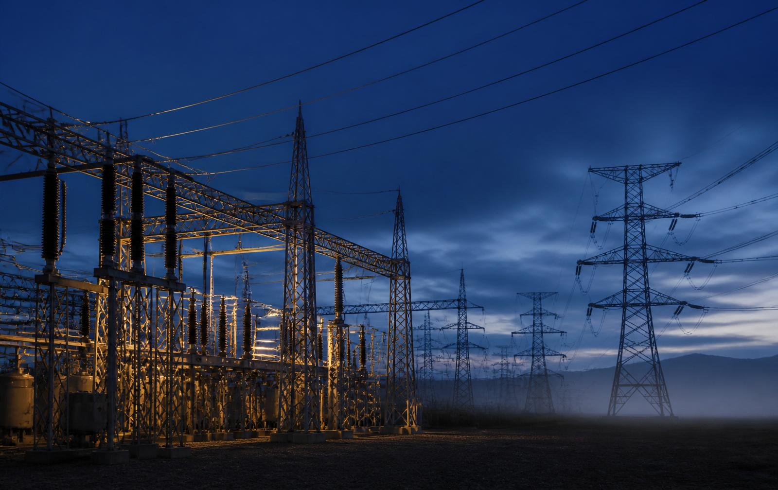 High-voltage substation and transmission towers at blue hour