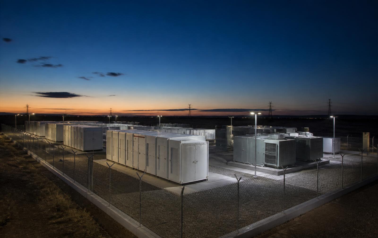 Containerised battery energy storage units at twilight in western India.